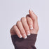 Classic white-tipped French manicure on natural nails with dark sweater cuff.