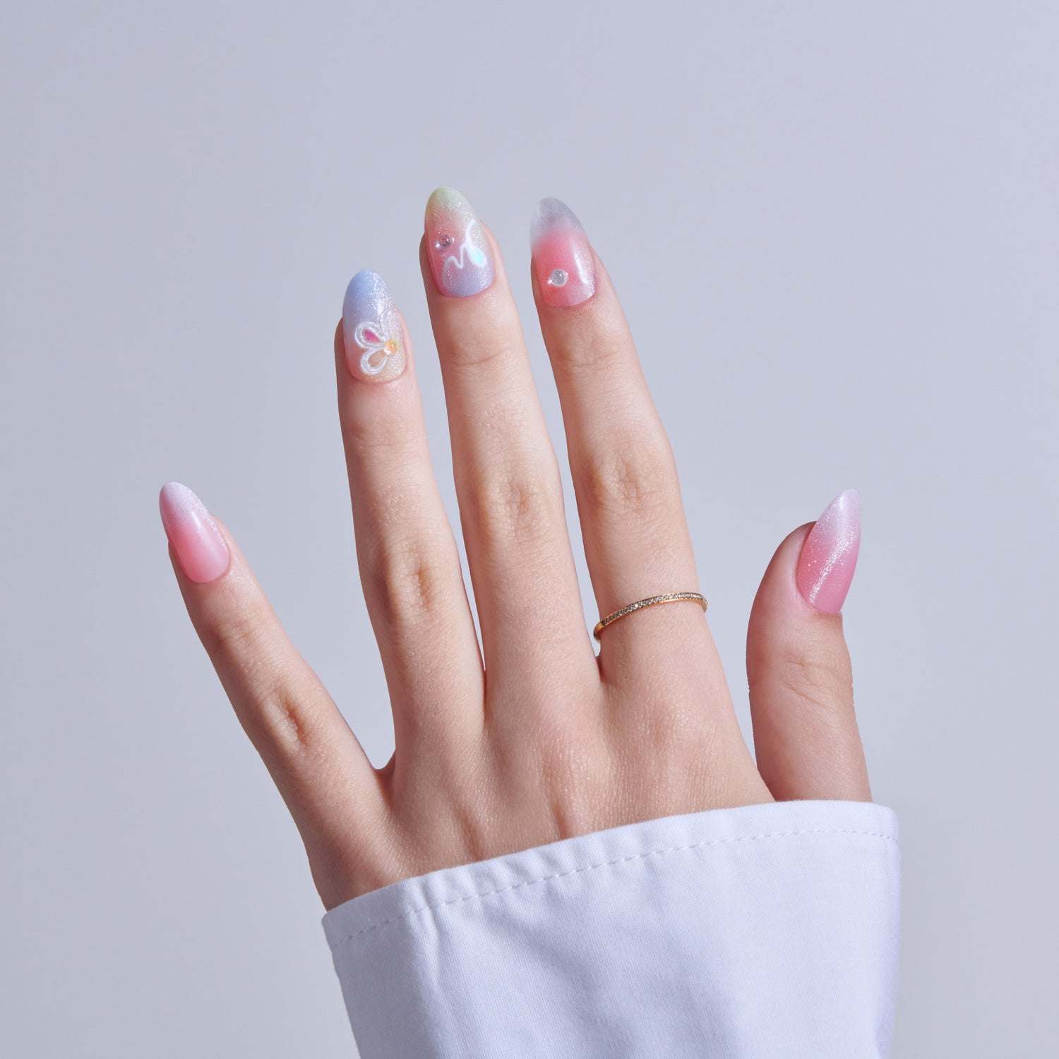 Hand displaying gradient nail art in pink, purple, and white with decorative swirls.