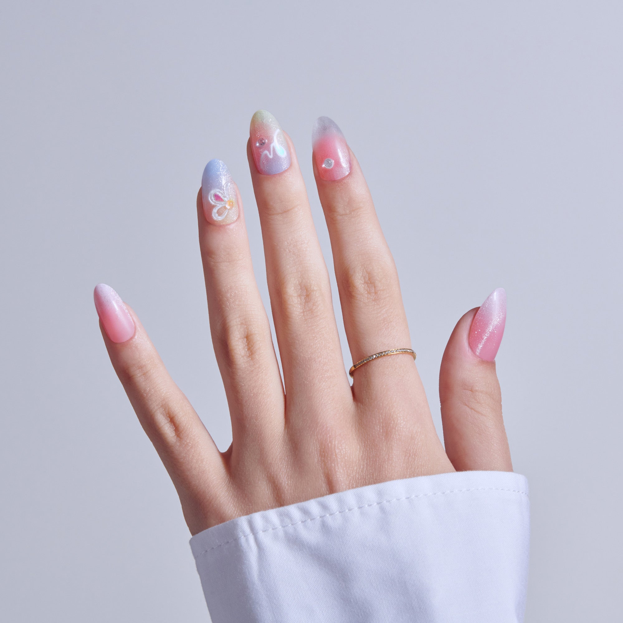 Hand displaying gradient nail art in pink, purple, and white with decorative swirls.