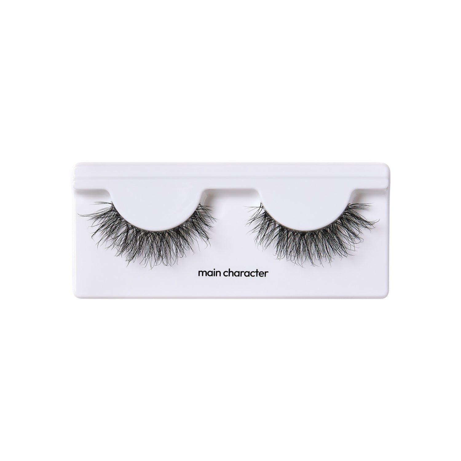The image shows a pair of false eyelashes in a white plastic case. The eyelashes are thick and voluminous, with a wispy, natural look. The case has two semi-circular indentations where the eyelashes are placed. Below the indentations, the text "main character" is printed in black. The overall presentation is clean and minimalistic.