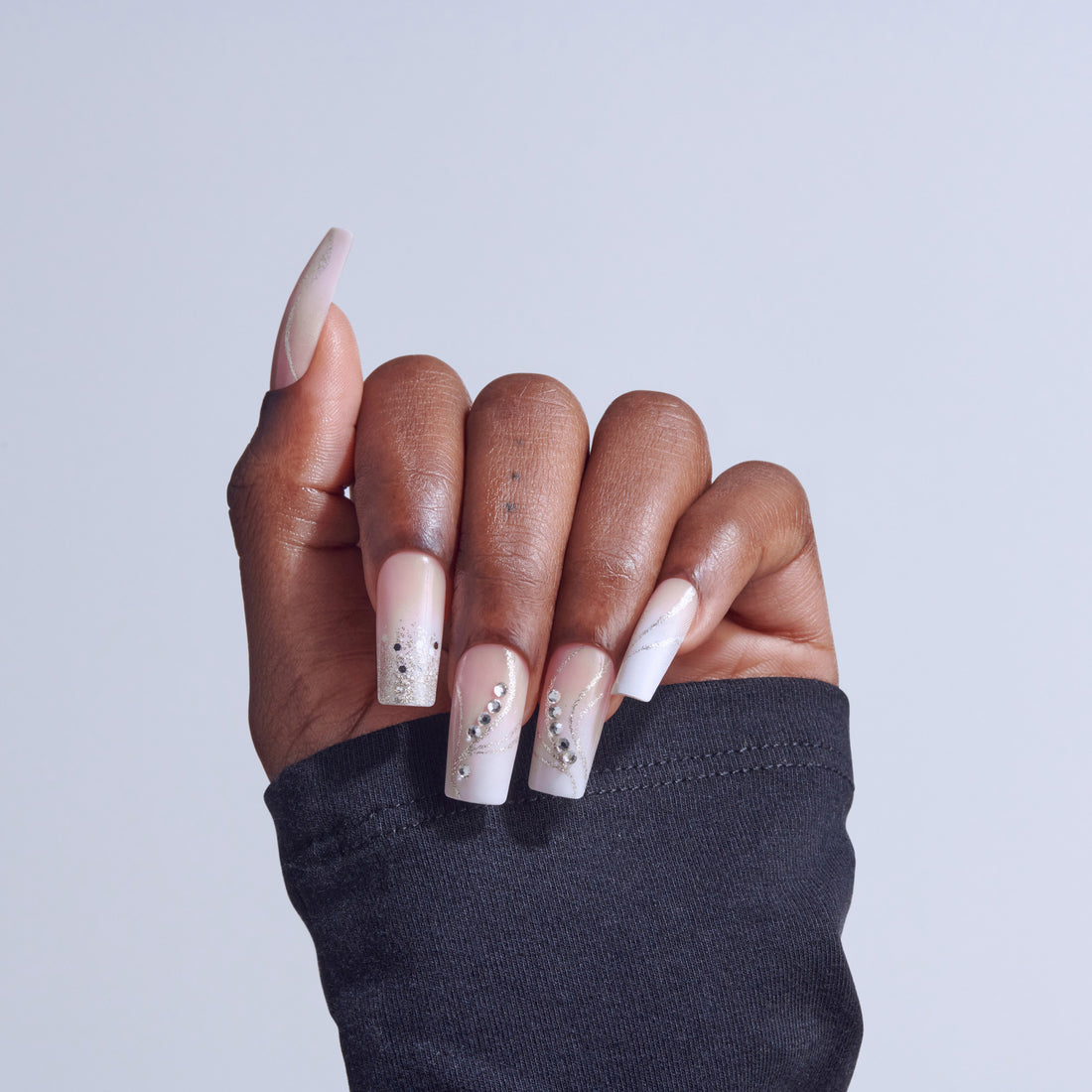 Hand displaying coffin-shaped acrylic nails with white ombre and rhinestone embellishments.