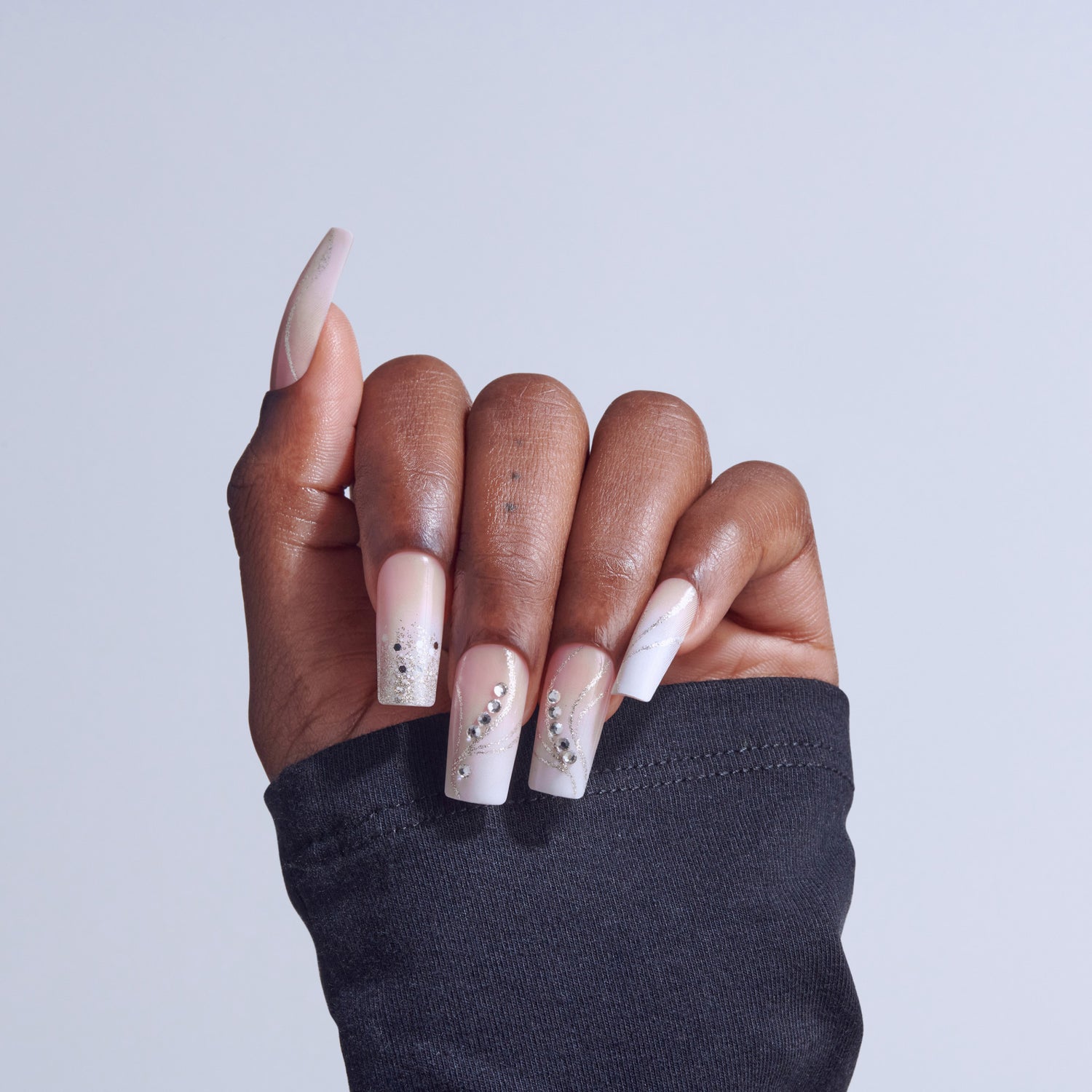 Hand displaying coffin-shaped acrylic nails with white ombre and rhinestone embellishments.