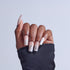 Hand displaying coffin-shaped acrylic nails with white ombre and rhinestone embellishments.