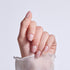 Manicured hand with pink nails decorated with white and yellow daisy flowers.
