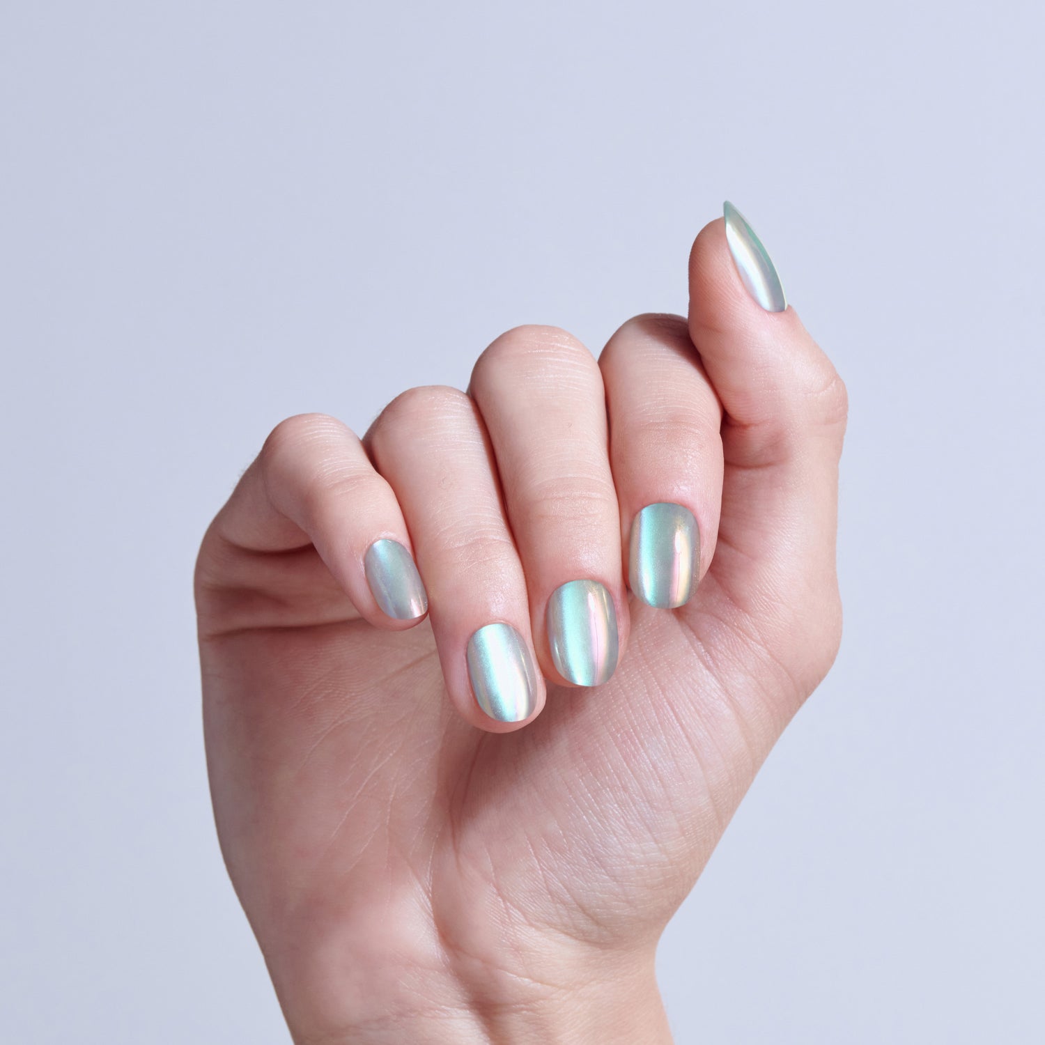 Hand displaying metallic chrome nail polish in silver and green iridescent finish on almond nails.