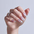 Hand displaying pink pearl chrome nails with almond shape and silver rings.