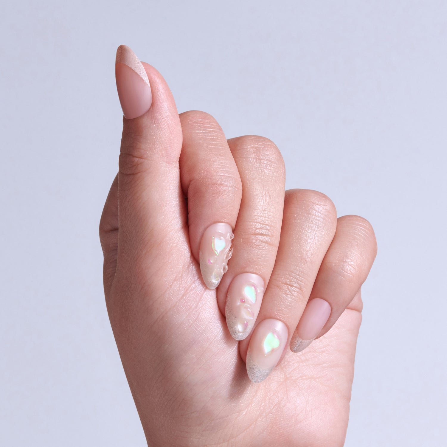 Hand displaying almond-shaped nails with iridescent pearl nail polish and rhinestone accents.
