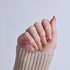 Hand displaying almond-shaped nails with gold and nude gradient nail art design.