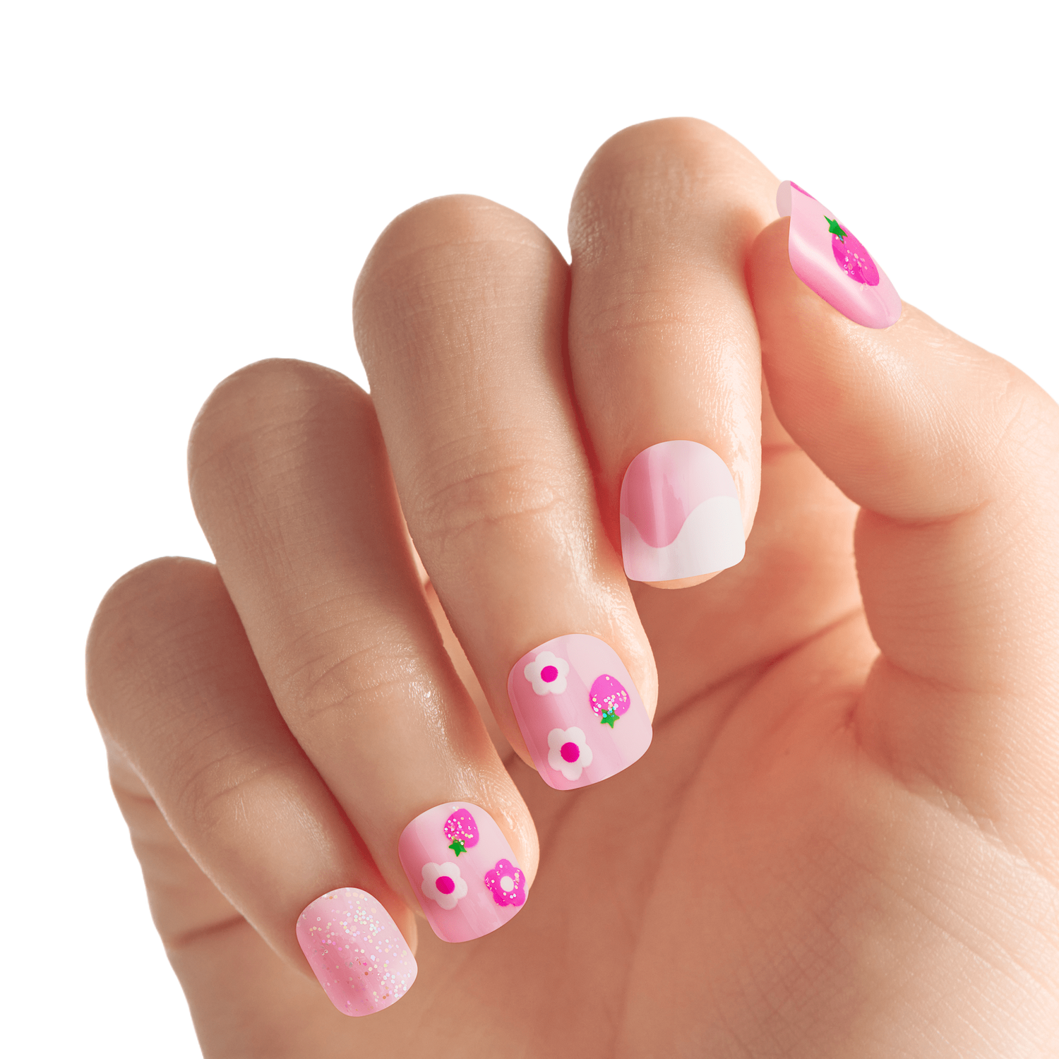 Child’s hand showing short, square, pink press-on nails with playful designs including strawberries, white and purple flowers, and glitter accents.