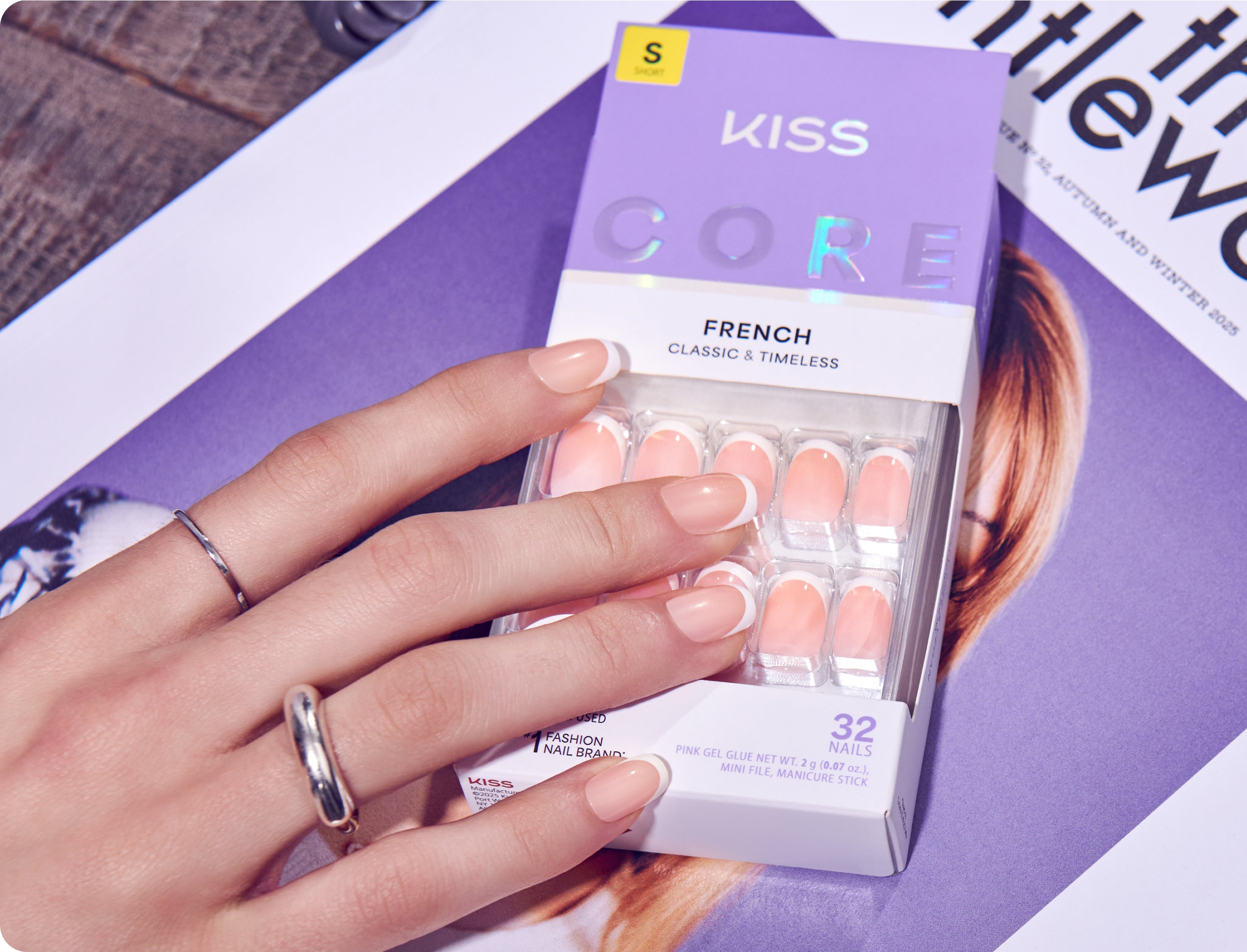 Hand holding KISS Core French Classic & Timeless press-on nails with 32-piece set packaging.