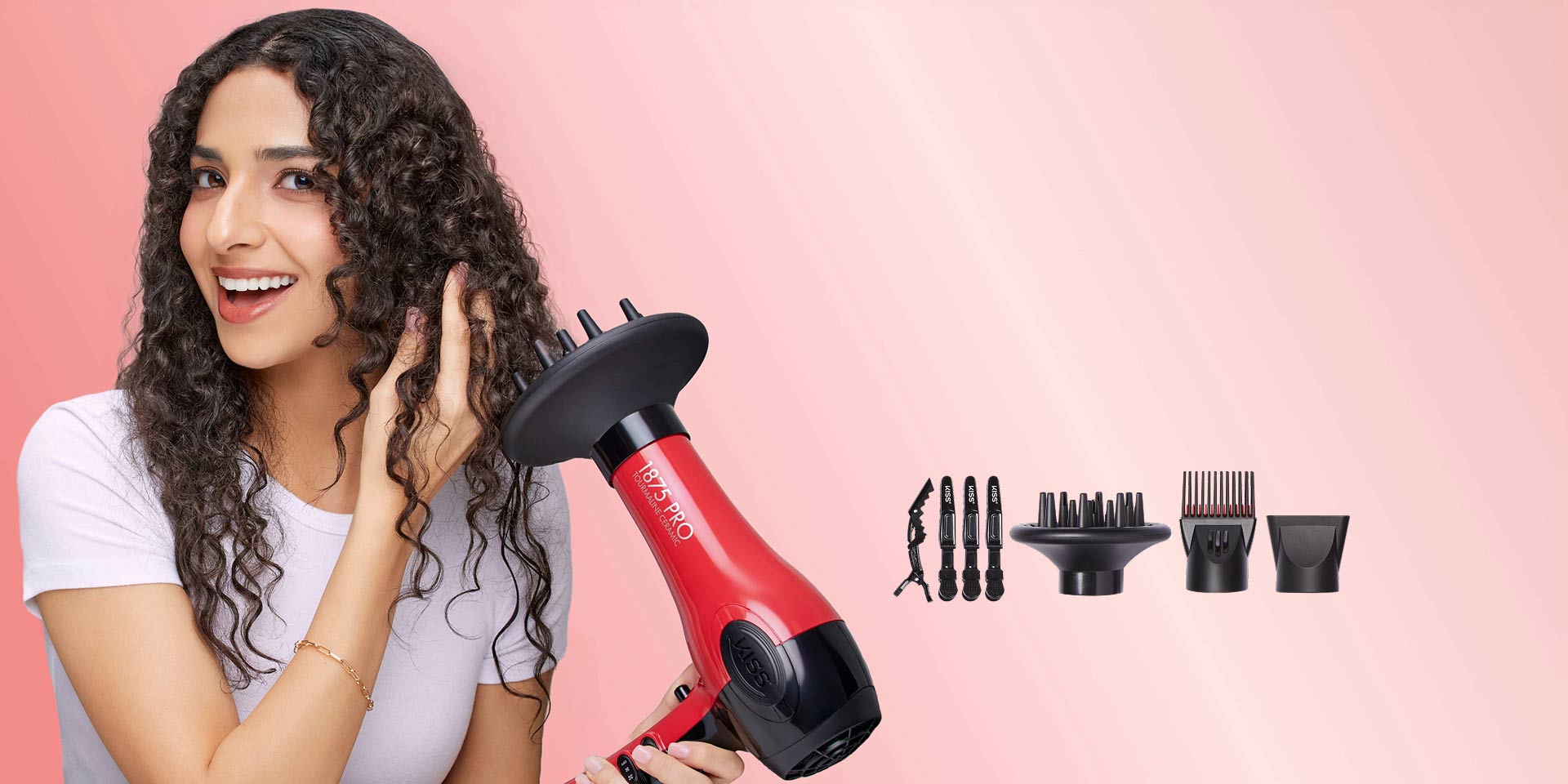 Woman with curly hair holding red KISS hair dryer with attachments displayed on pink background.