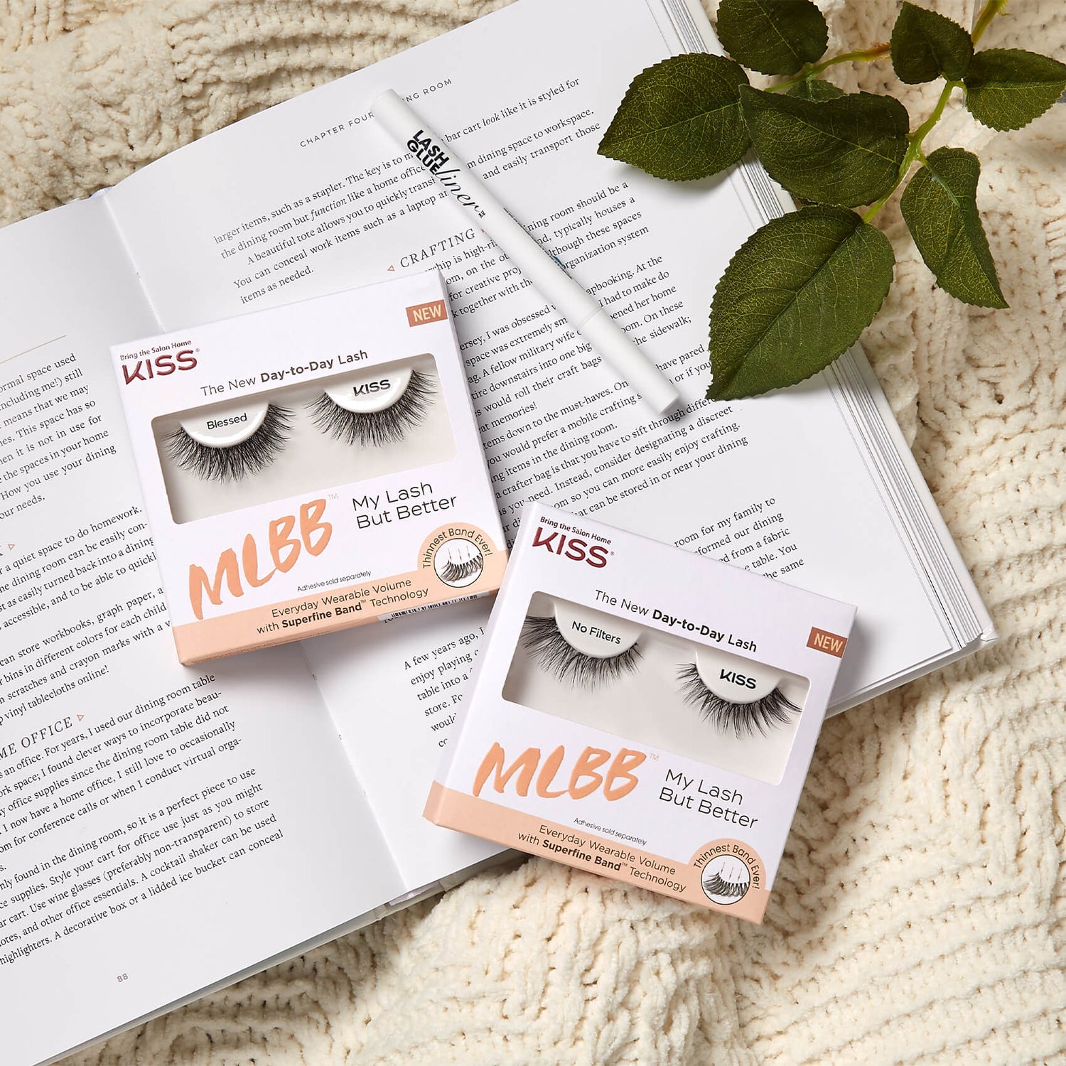 Two boxes of KISS Day-to-Day Lash on an open book with a plant in the background.