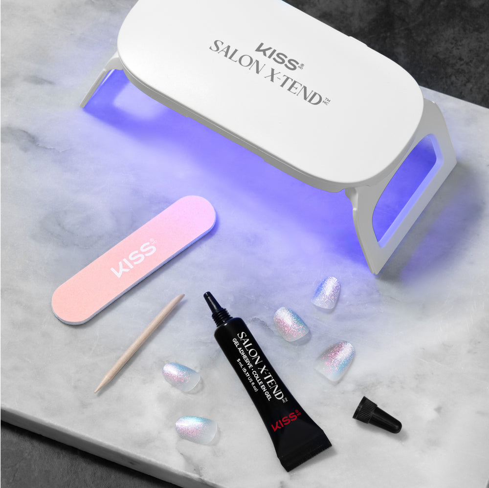 KISS Salon X-Tend UV lamp with nail file, gel brush, and glitter nail samples on marble.