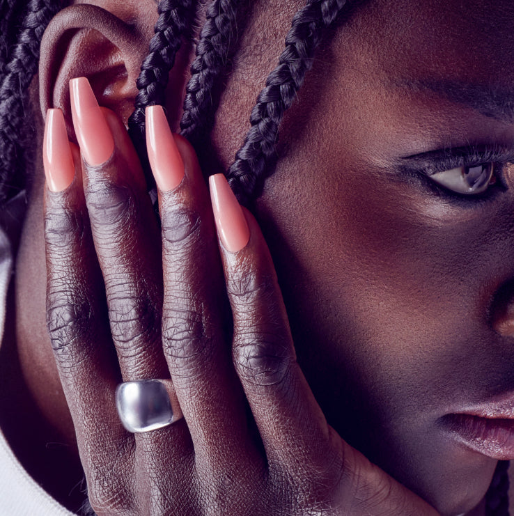 Woman with long pink and white ombre nails touching her face near braided hair.