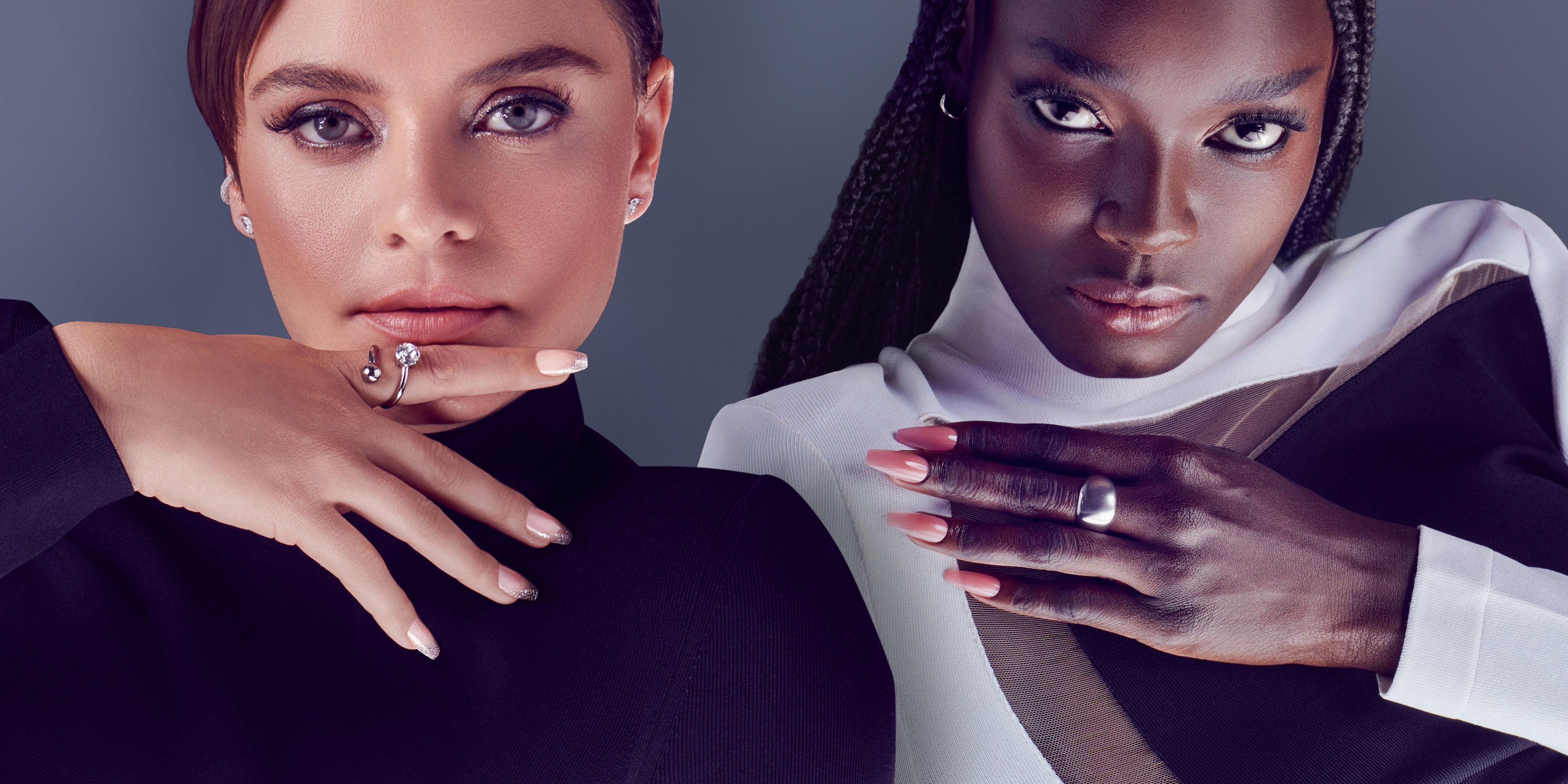 Two women displaying manicured nails with rings against gray background.