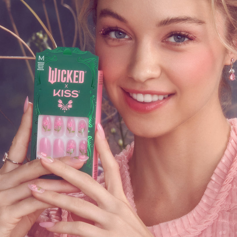 Woman holding Wicked x Kiss nail set with pink floral designs, size M.