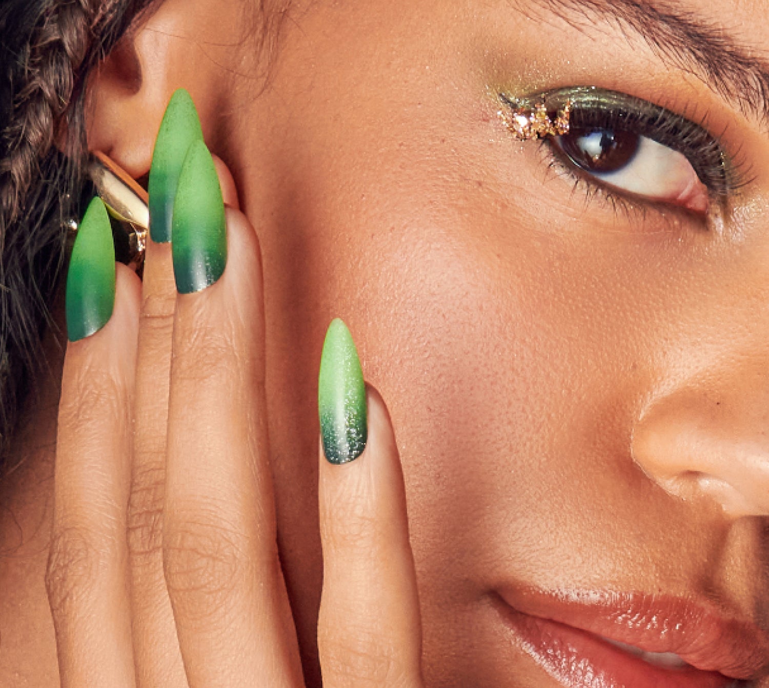 Woman with green ombre nails and gold glitter eyeshadow, close-up beauty shot.