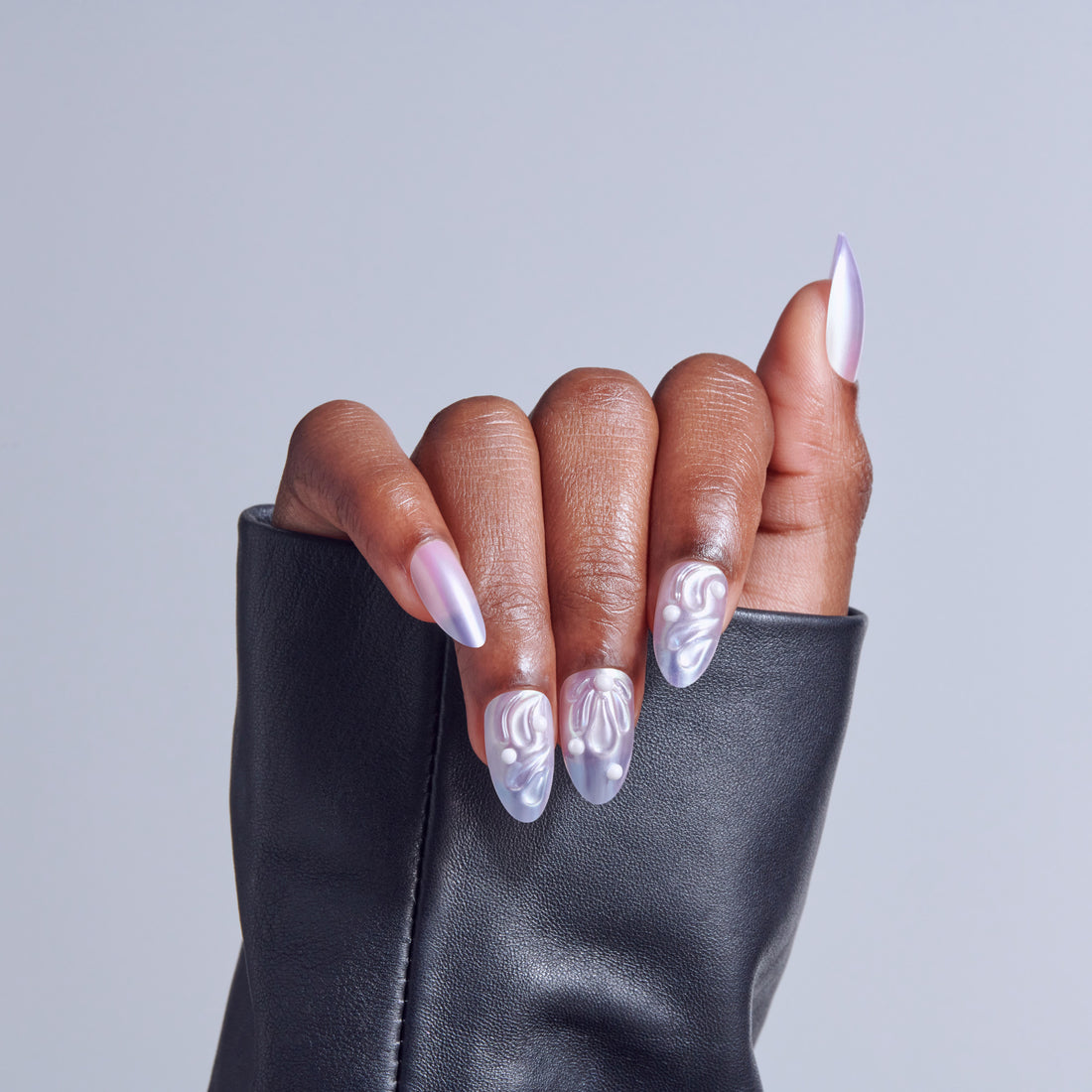 Hand displaying almond-shaped nails with lavender ombre and swirl nail art design.