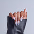 Hand displaying almond-shaped nails with lavender ombre and swirl nail art design.
