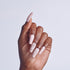 Hand with pale pink coffin-shaped nails, some adorned with pearl beads, against white background.