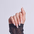 Hand displaying almond-shaped nails with pink and white ombre manicure design.