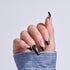 Manicured nails with black glitter tips and pink base, decorated with star and rhinestone accents.