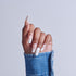 Hand with almond-shaped nails featuring white tips and decorative patterns, wearing blue denim sleeve.