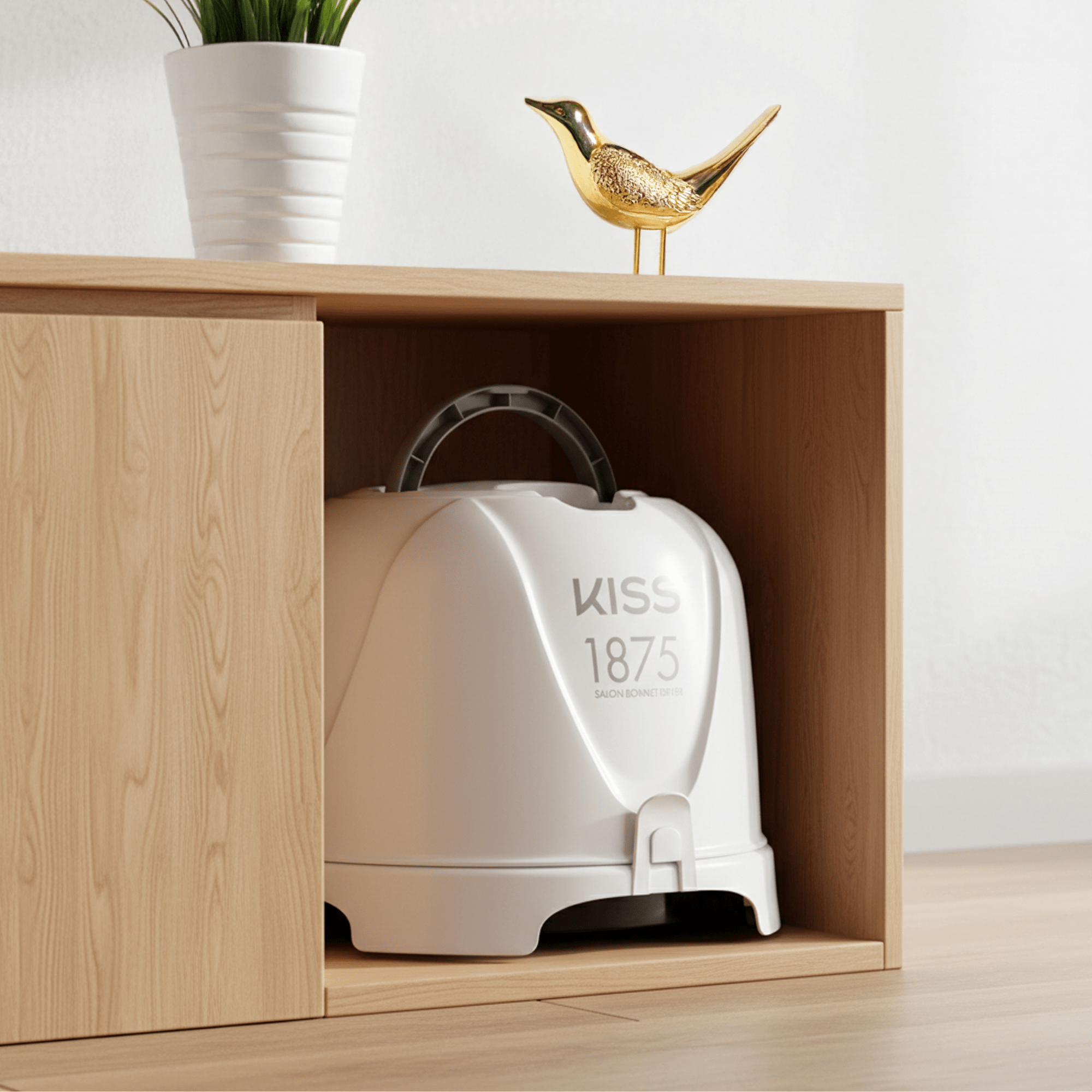 White KISS 1875 salon bonnet hair dryer stored inside a light wood cubby with a white plant pot and gold bird figurine on top.