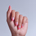 Hand displaying pink ombré almond nails against light blue background.