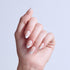 Hand displaying French manicure nails with white tips against light blue background.