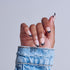 Hand with black and white ombre nails wearing distressed blue denim cuff.