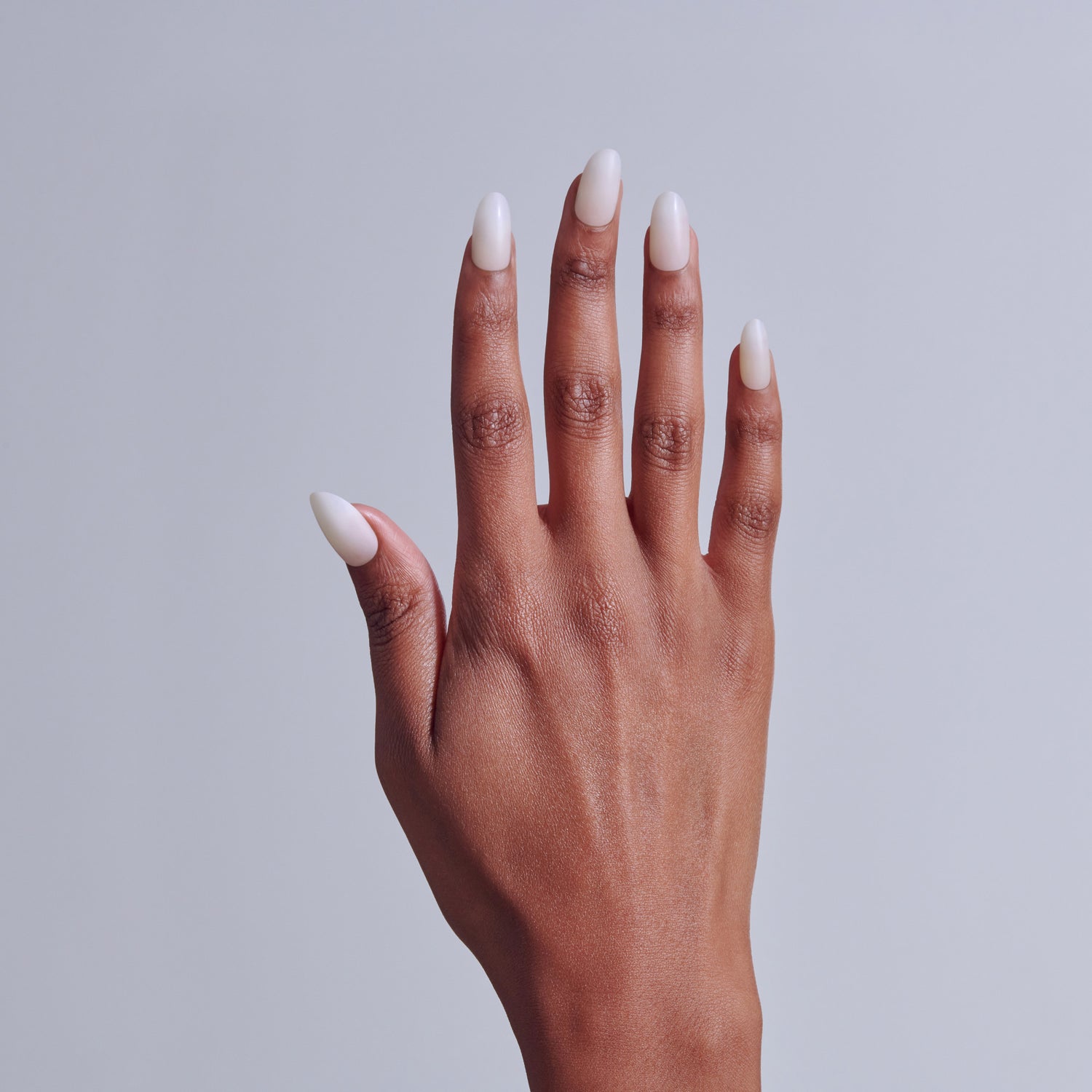 Hand with white ombre nail polish against gray background