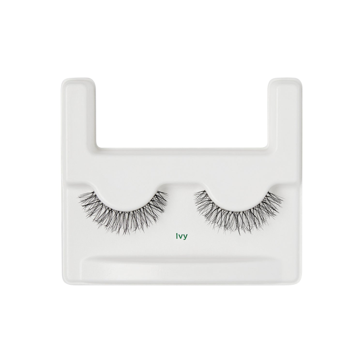 The image shows a pair of false eyelashes displayed on a white plastic tray. The tray has a rectangular shape with a U-shaped cutout at the top. The eyelashes are arranged side by side, with the label "Ivy" printed in green text below them. The lashes are dense and have a natural, wispy appearance.