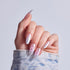 Manicured hand displaying almond nails with pink pearl polish and floral nail art designs.