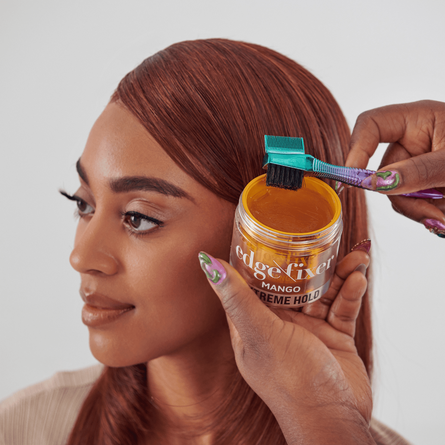 Woman with smooth, styled brown hair held by hands applying KISS Colors &amp; Care Edge Fixer Extreme Hold Gel in mango with a purple and teal brush.