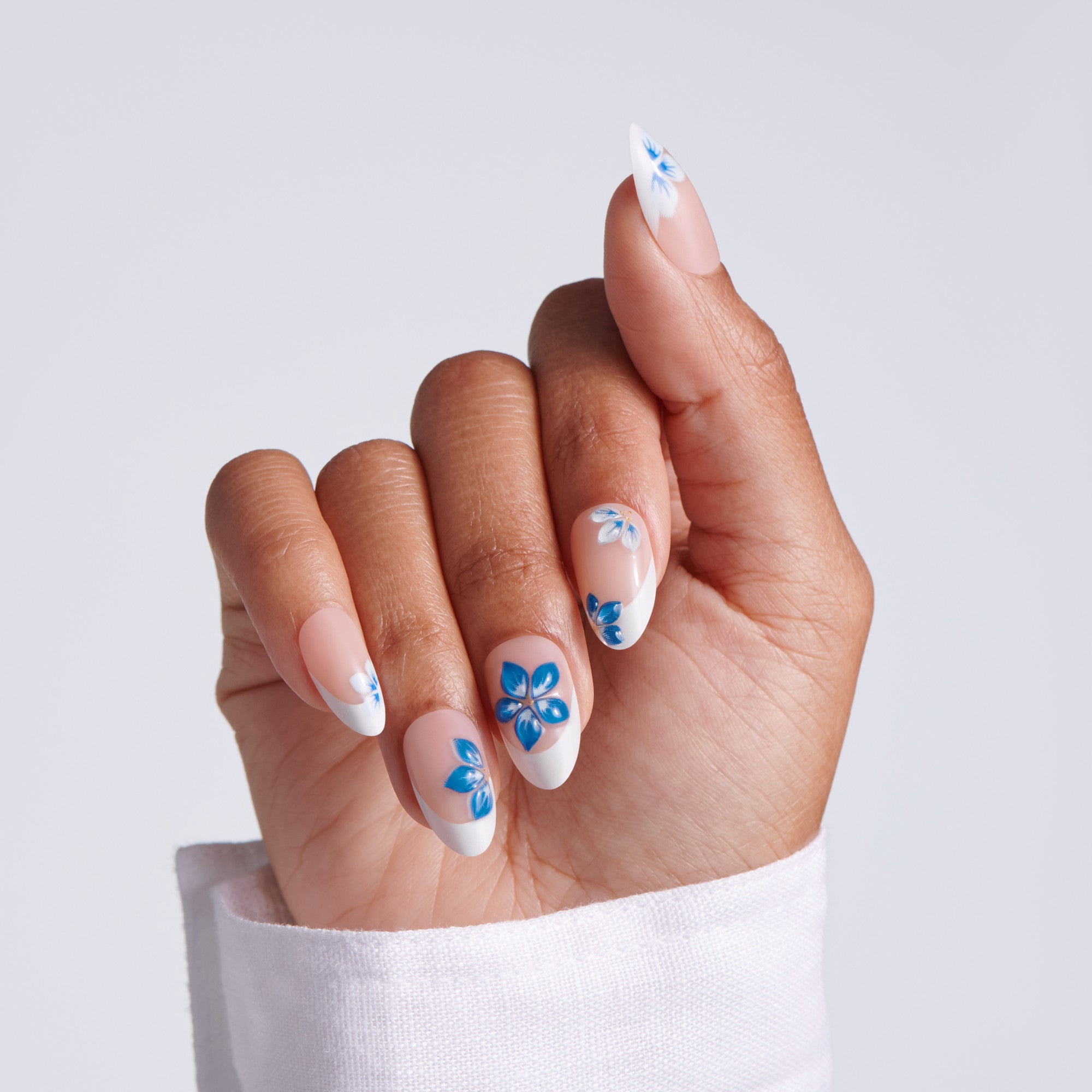 Hand with blue floral nail design on a light gray background