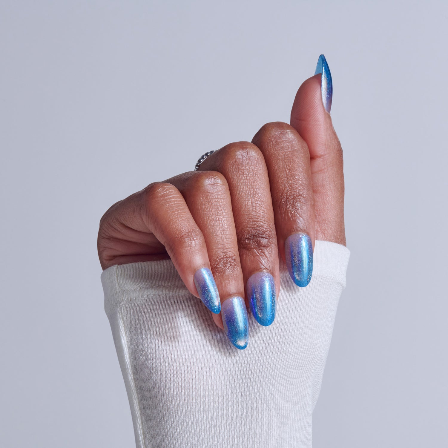 Blue chrome gel manicure with almond nails on white sleeve background.