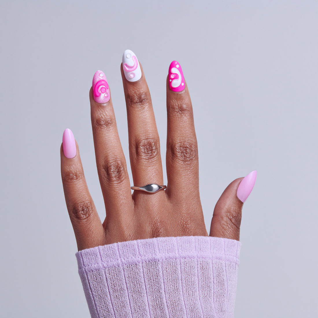 Hand displaying pink nail art designs with swirl patterns on white and bright pink nails.