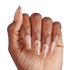 The image features a hand with elegantly manicured nails. The nails are long and shaped with a slight square tip. The base color is a soft nude, complemented by a shimmering gold glitter at the tips. Some nails are adorned with decorative elements, including small gold beads and intricate designs, adding a touch of glamour. The hand is positioned against a plain white background, highlighting the nail art&