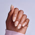 Close-up of hand displaying nude and white ombre acrylic nails against light background.