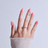Hand with pink almond nails and silver chain ring against white background