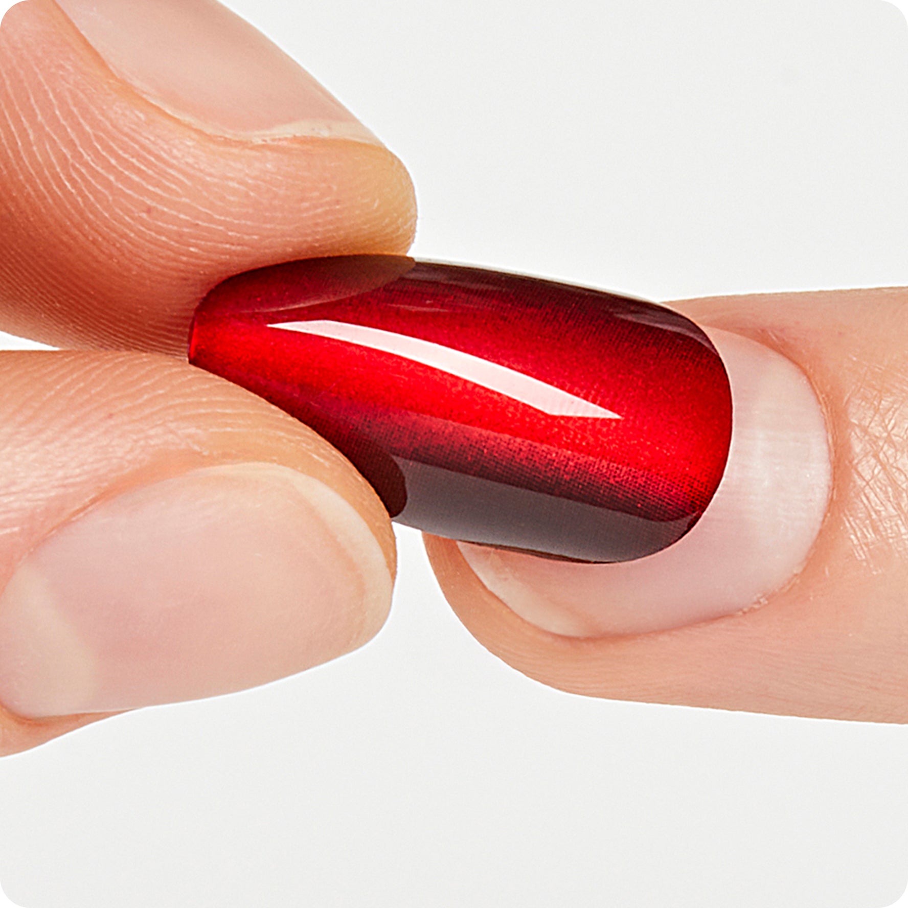 Red nail polish with white stripe on natural nail against white background.