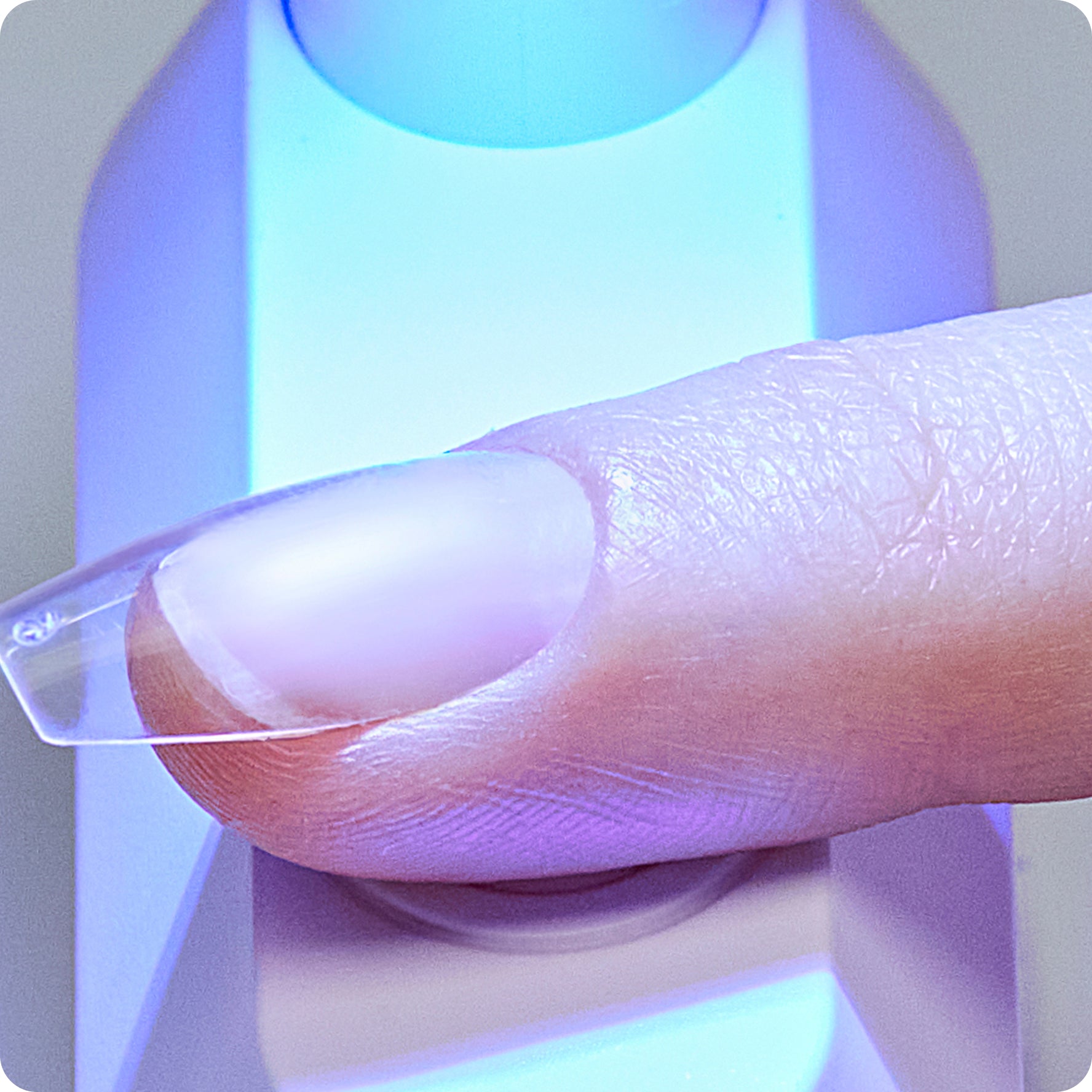 Close-up of a hand holding a clear plastic slide with a purple light in the background