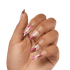 A hand with medium brown skin tone displaying long, coffin-shaped press-on nails in a clear base with shiny pink and metallic rose gold drip designs.