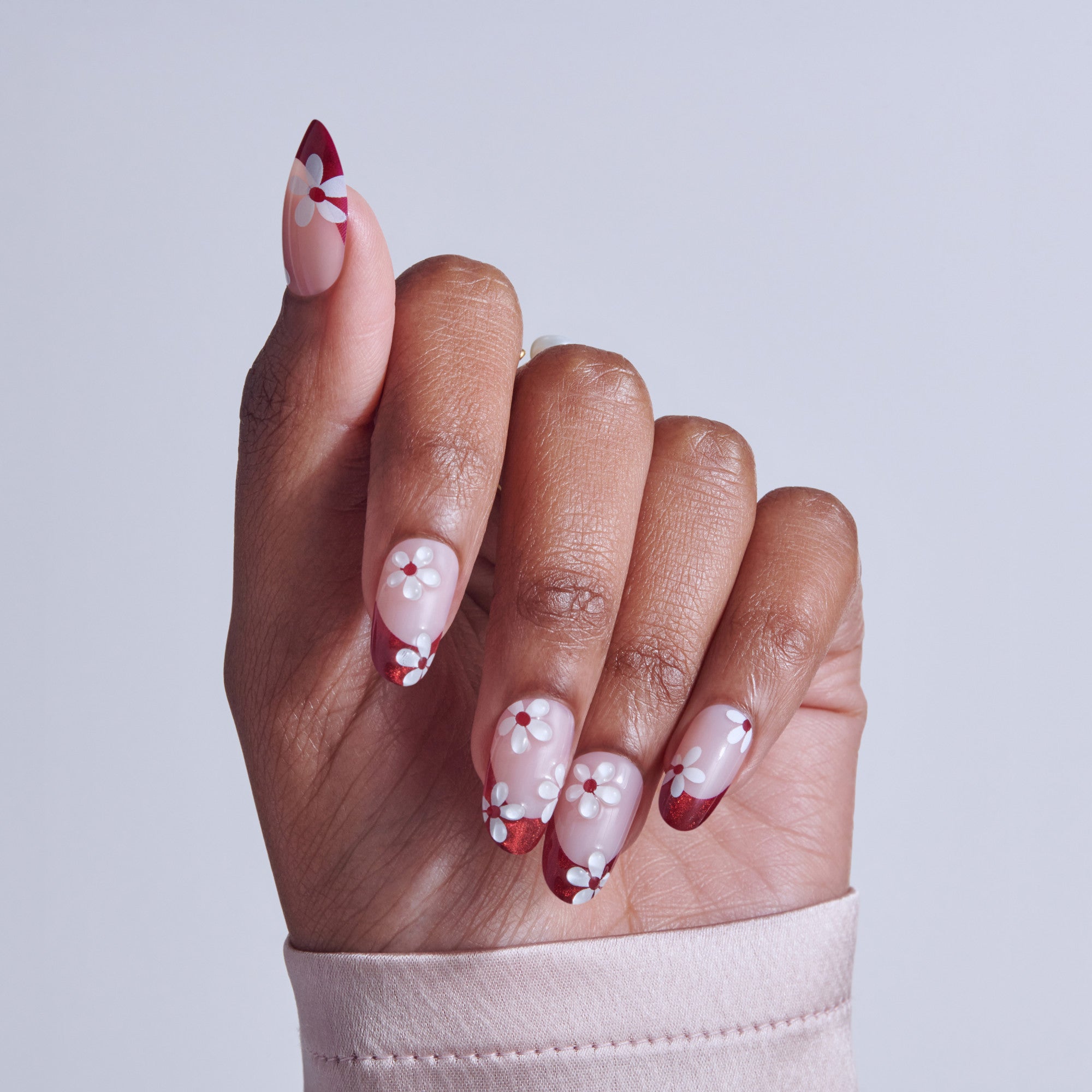 Almond nails with red and white floral nail art design on neutral background.