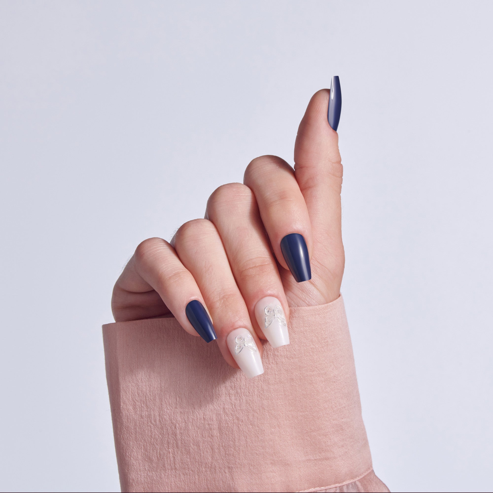 Hand displaying navy and white manicure with decorative nail art on beige fabric background.