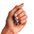 Hand with medium brown skin tone displaying matte ombre press-on nails in teal and soft pink shades, showing short to medium almond shape.