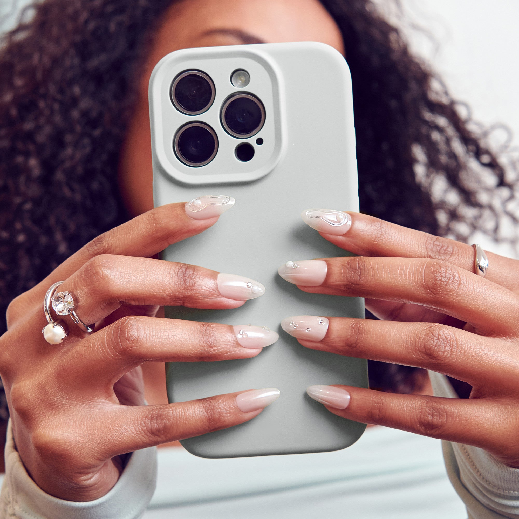 Woman holding white iPhone 14 Pro with manicured nails and diamond ring