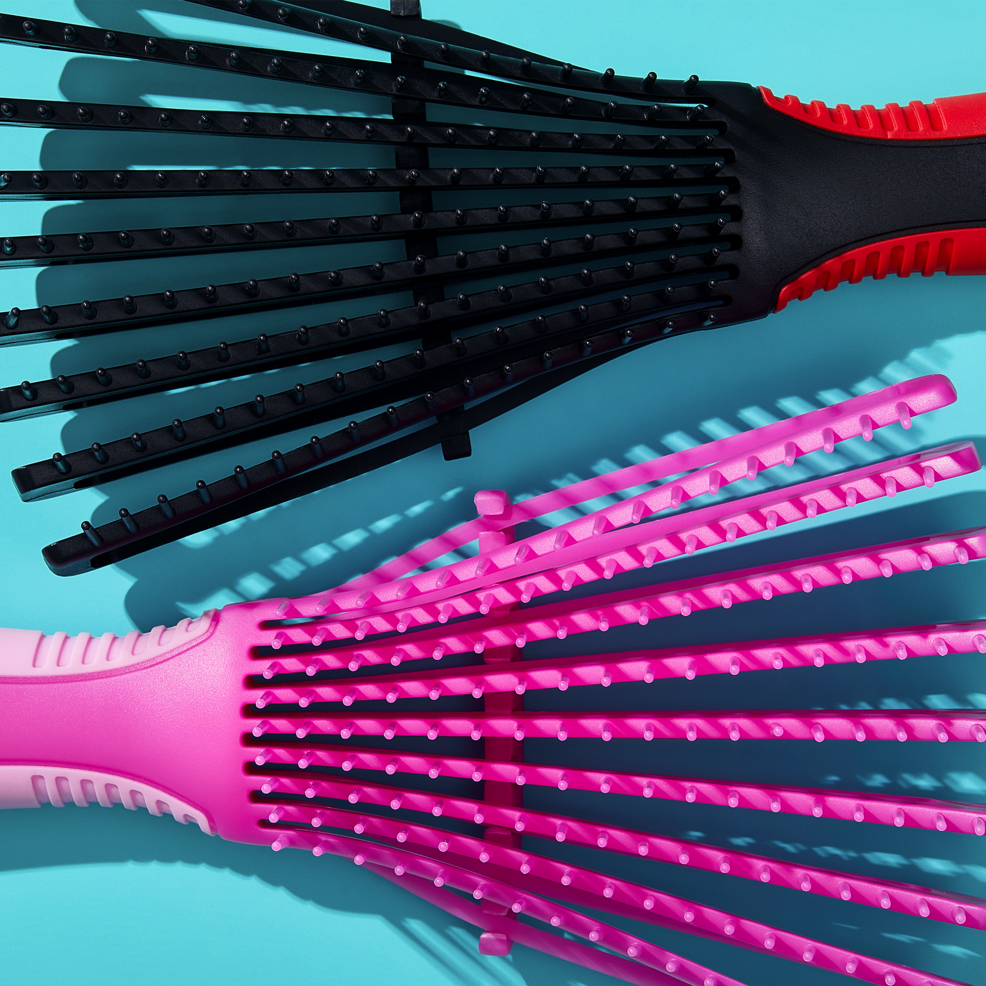 Two KISS Colors &amp; Care Glide &amp; Define non-slip detangling brushes, one black with red handle and one bright pink with light pink accents, shown from the top on a blue background.