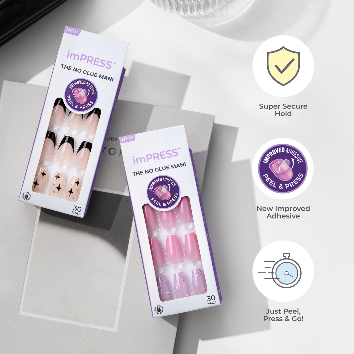 Two boxes of imPRESS Press-On Manicure set on a neutral surface, one with nude nails featuring black tips and star designs, the other with pink nails with glitter accents. Packaging highlights \